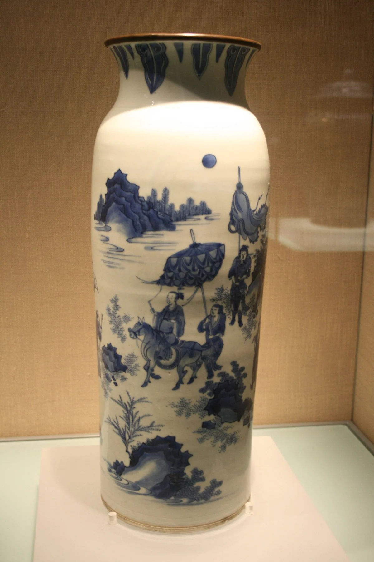 Een blauw-witte porseleinen vaas met figuren in een landschap.