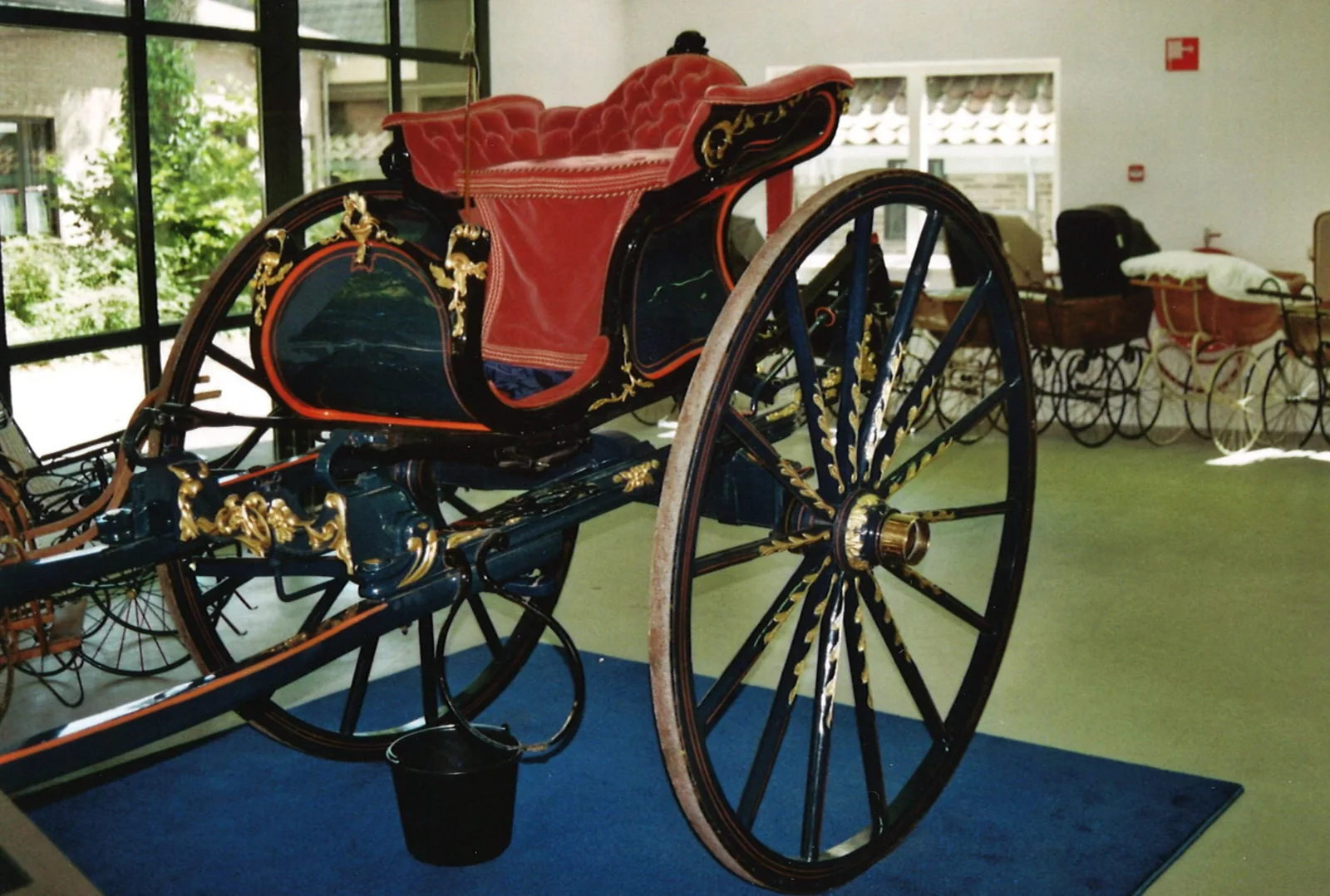Historische interieurfoto met een sjees en andere rijtuigen in Museum Vreeburg.