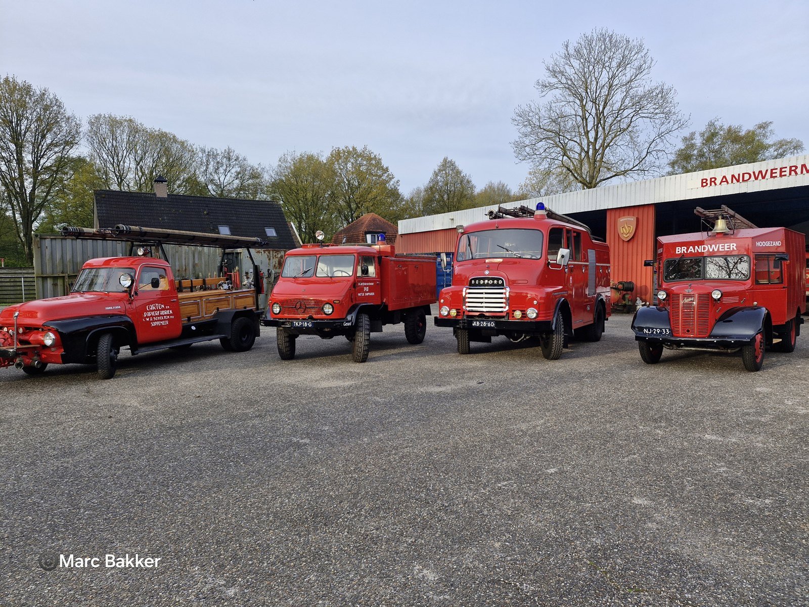 Various red fire engines on the outdoor grounds in front of the museum hall.