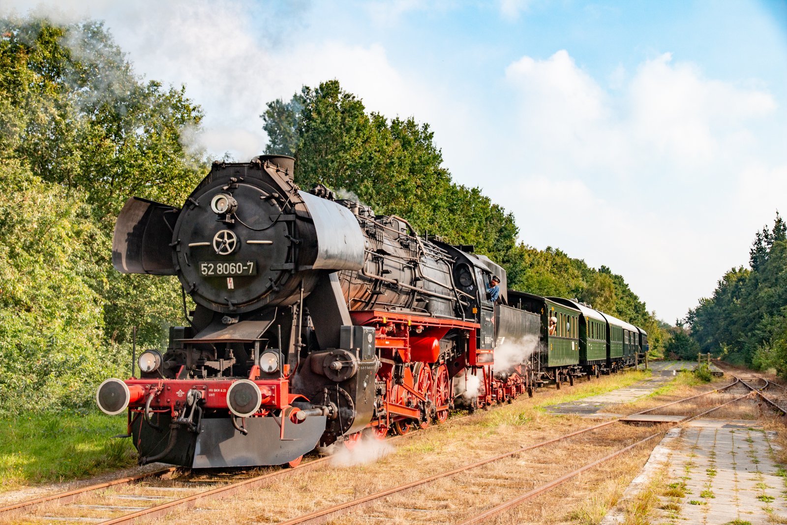 Stoomlocomotief met rijtuigen op het spoor.