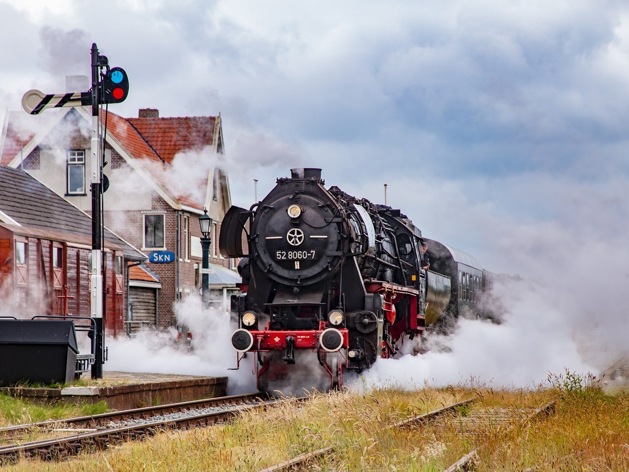Steam locomotive at a platform, surrounded by steam.