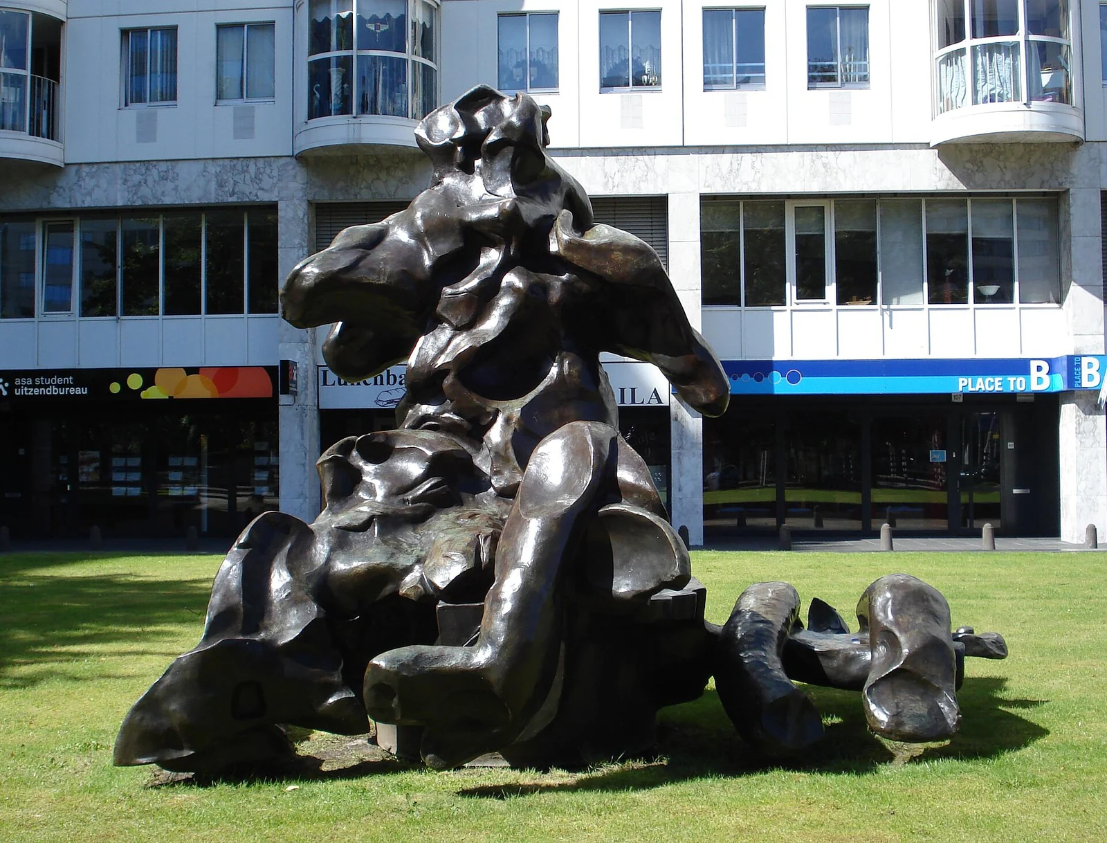 Weetje: deze foto toont De Koonings bronzen Seated Woman op zijn vroegere plek bij het Weena in Rotterdam. Sinds 18 juli 2026 staat het beeld volgens BKOR tijdelijk op de kade bij Museum Fenix, waar De Kooning honderd jaar eerder naar New York vertrok; in 2027 keert het terug naar het Hofplein. Dit is geen opname van de Rijksmuseumtentoonstelling.