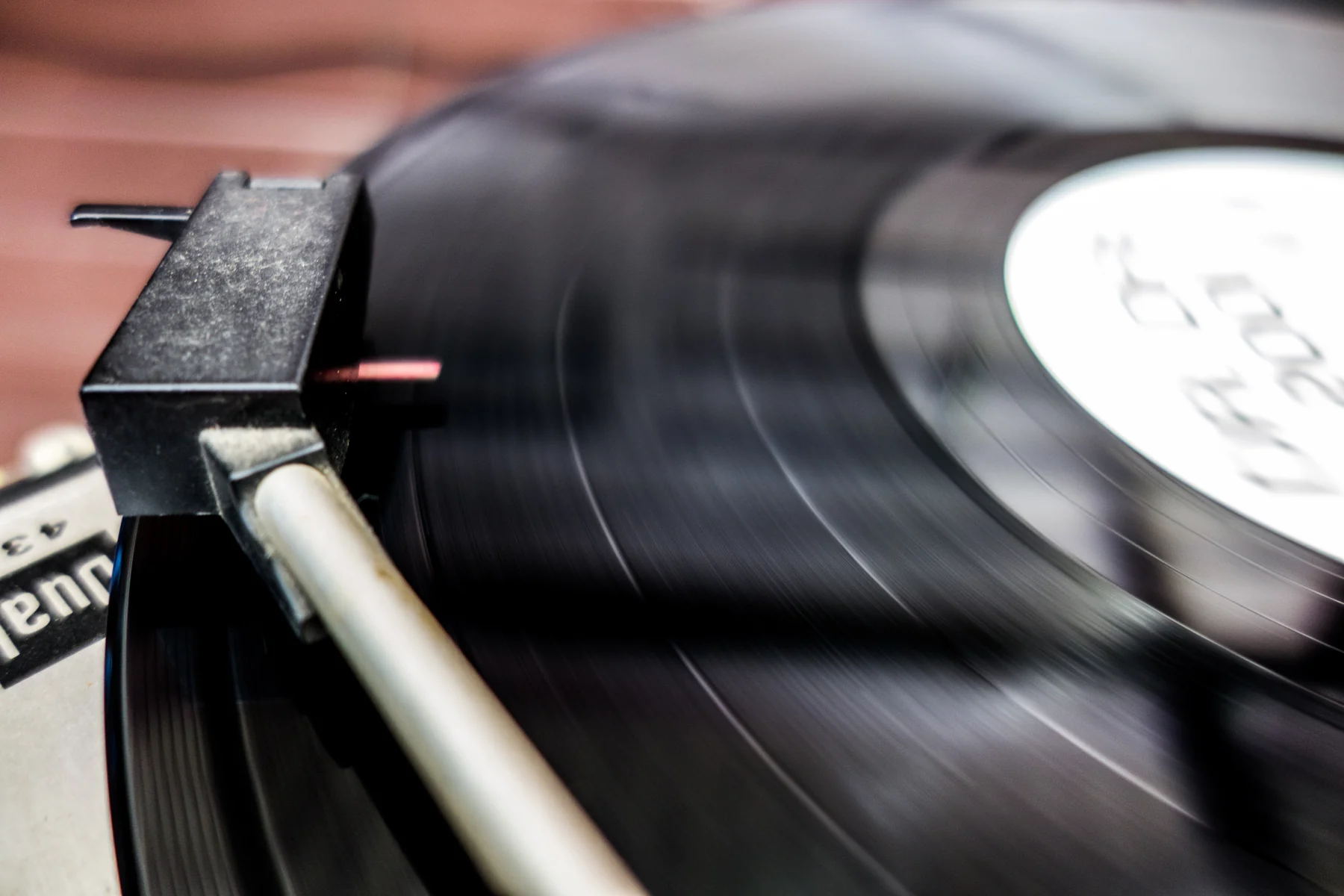 Naald en toonarm boven de groeven van een zwarte vinylplaat.