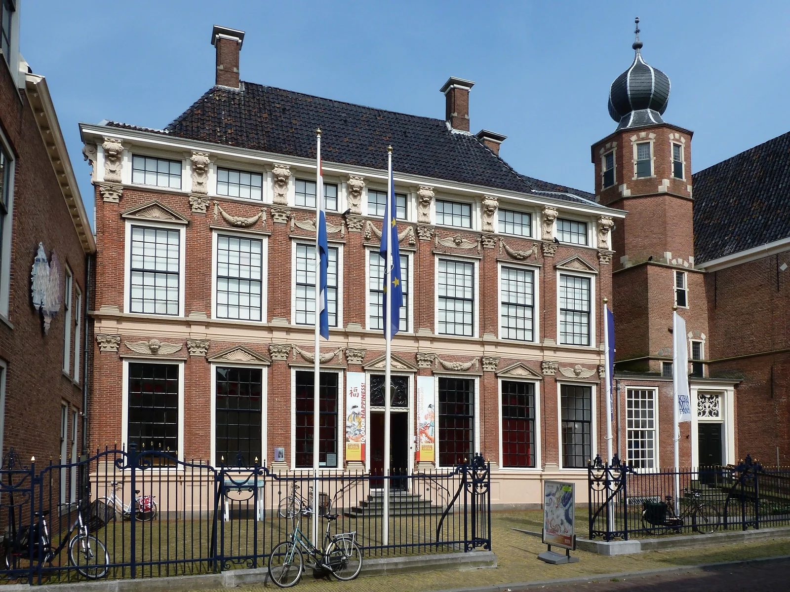 Rijk versierde bakstenen gevel van het Princessehof, met hoge ramen, vlaggen en een hek.