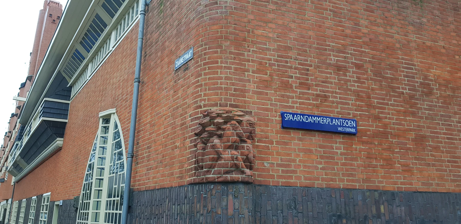 De bakstenen hoek van Het Schip met ramen en straatnaamborden.