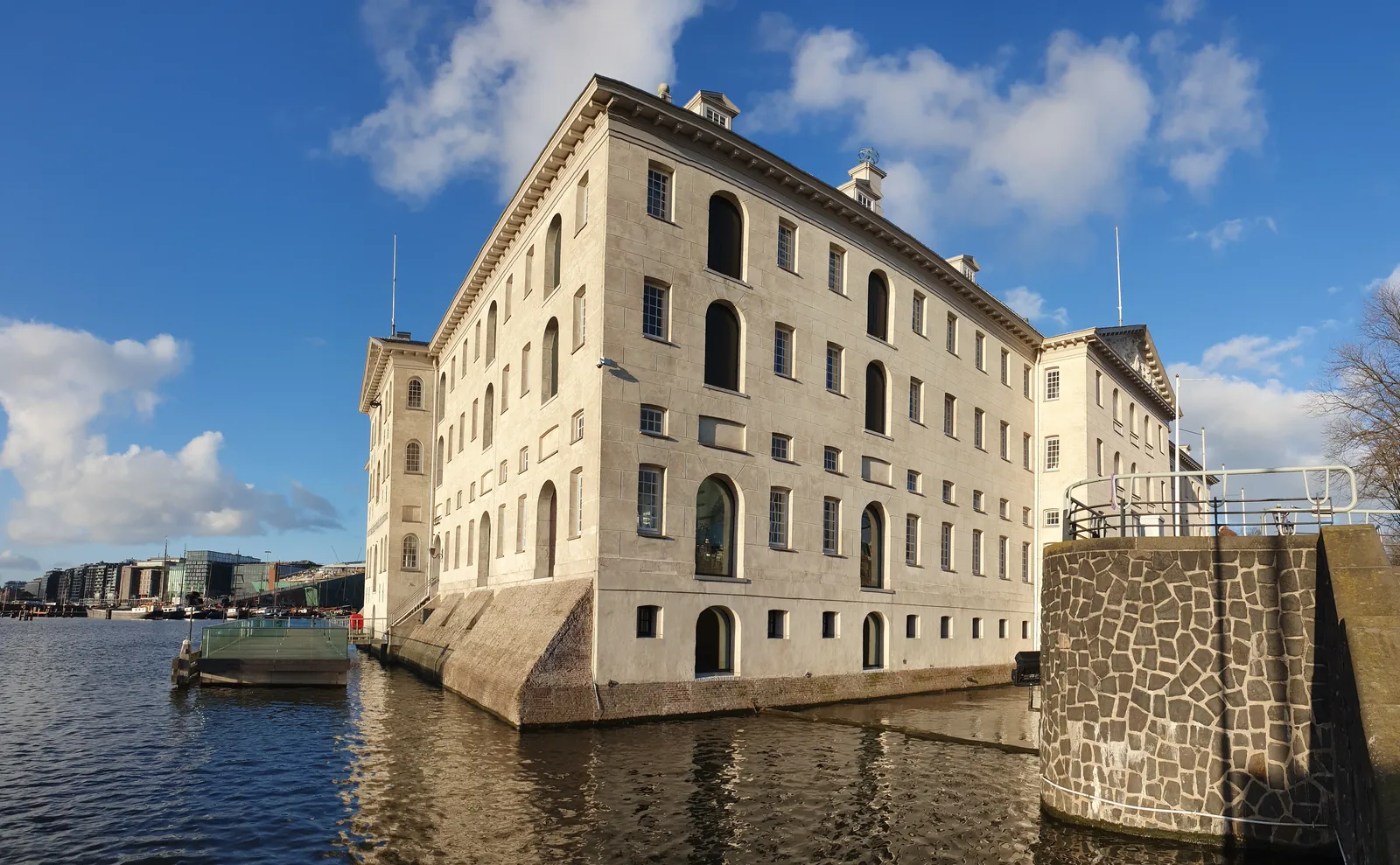 Side façade of Het Scheepvaartmuseum beneath a blue sky.