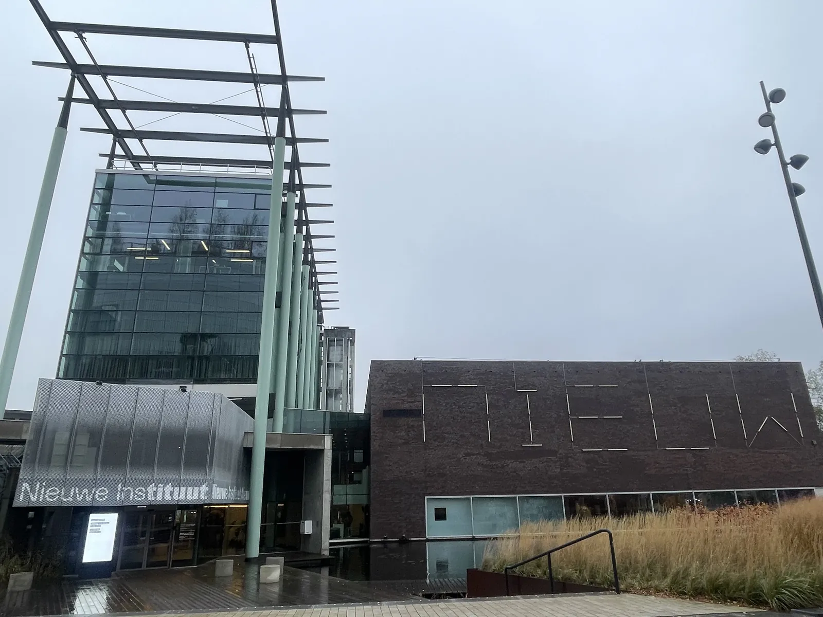 Moderne Fassade des Nieuwe Instituut mit Glasturm, dunkler Seitenwand und dem Namen des Museums.