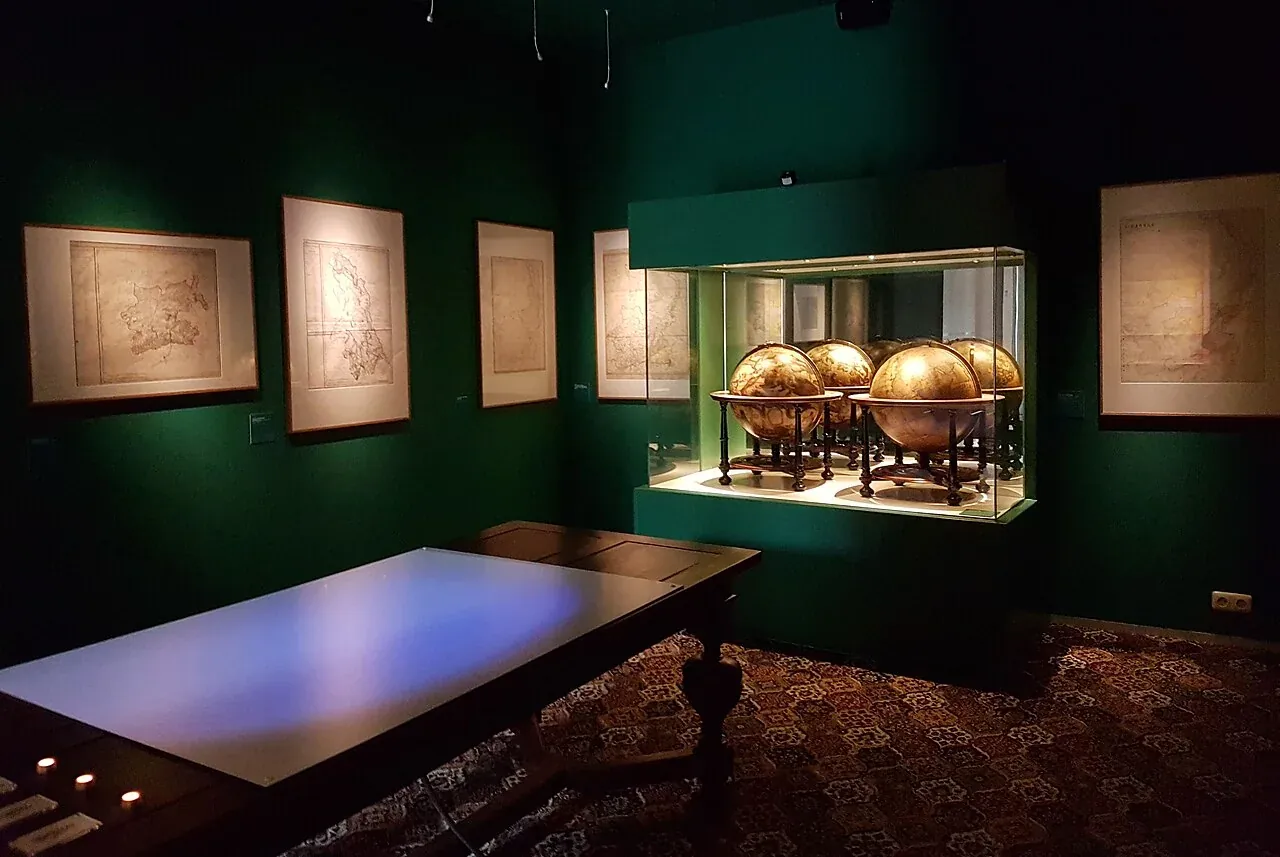 Historisch zaalbeeld met kaarten en globes in het Limburgs Museum.