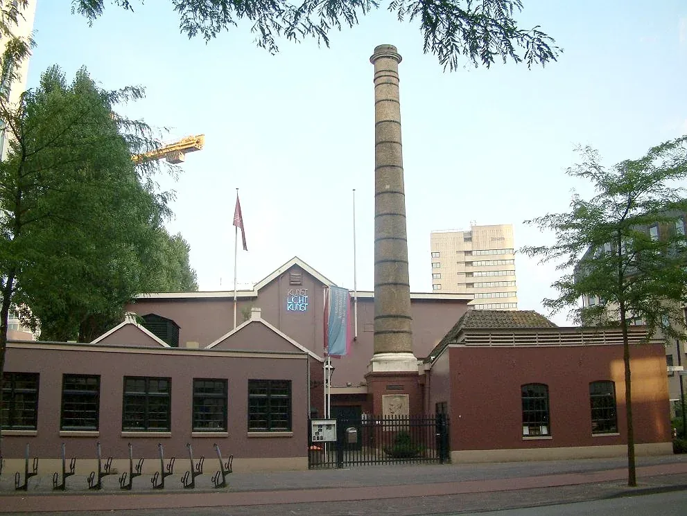 Laag industrieel gebouw met hoge schoorsteen aan de Emmasingel.