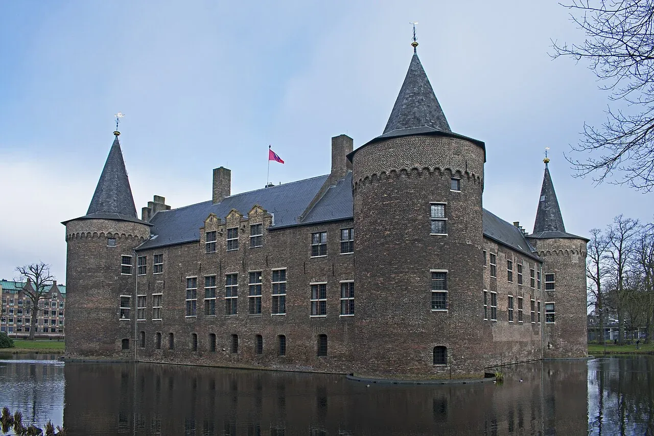 Bakstenen kasteel met ronde hoektorens, omgeven door een gracht.