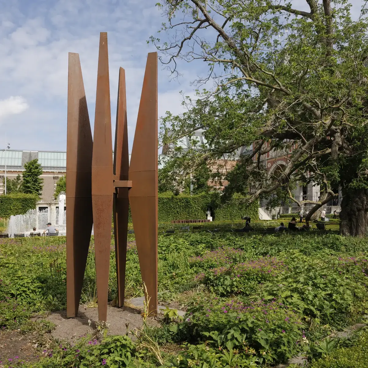 Het roestbruine stalen beeld Grote vier van Carel Visser tussen bomen in de Rijksmuseumtuinen.