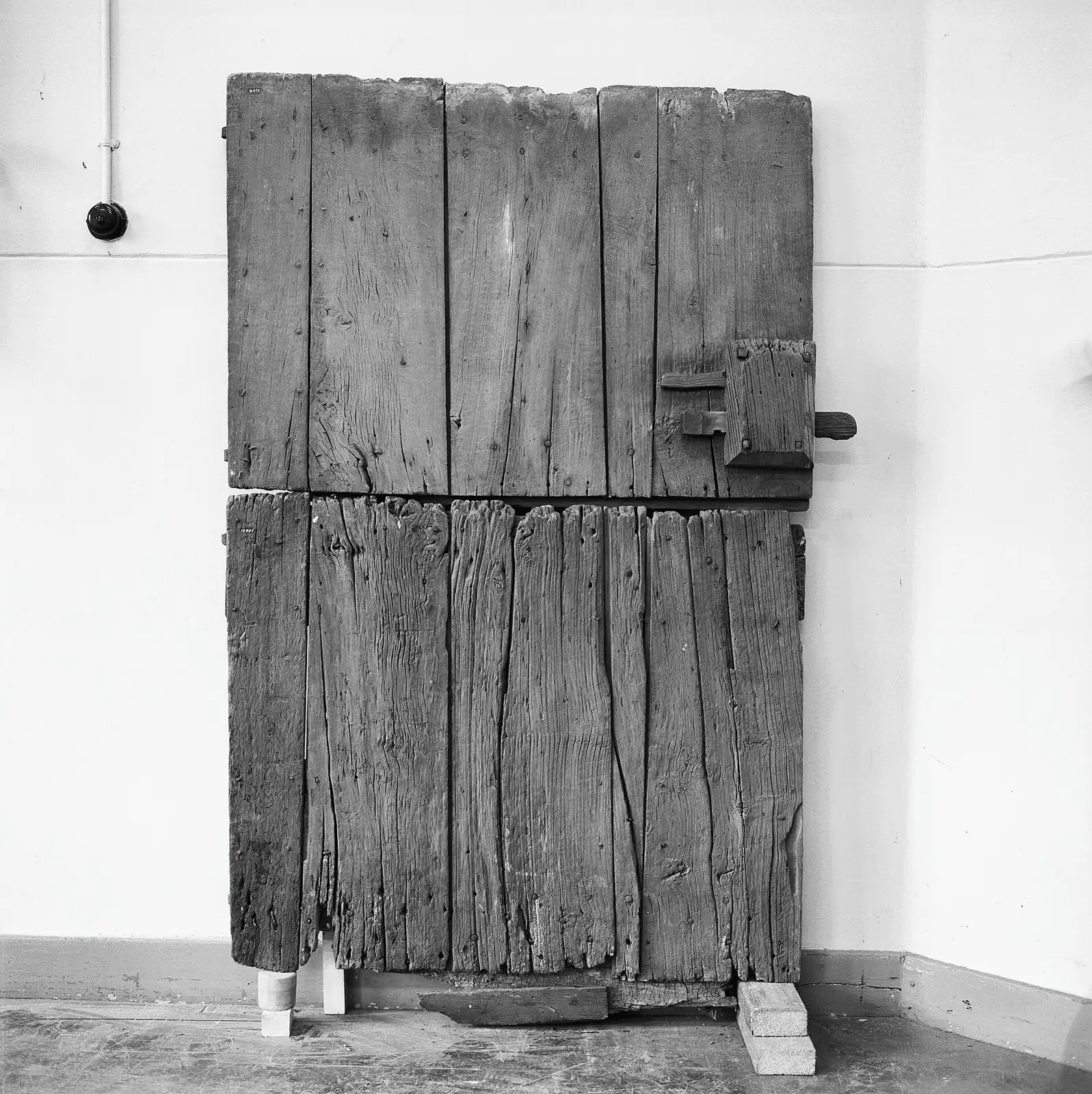 Oude houten deur met metalen hefslot in het gebouw aan de Kapittelstraat.