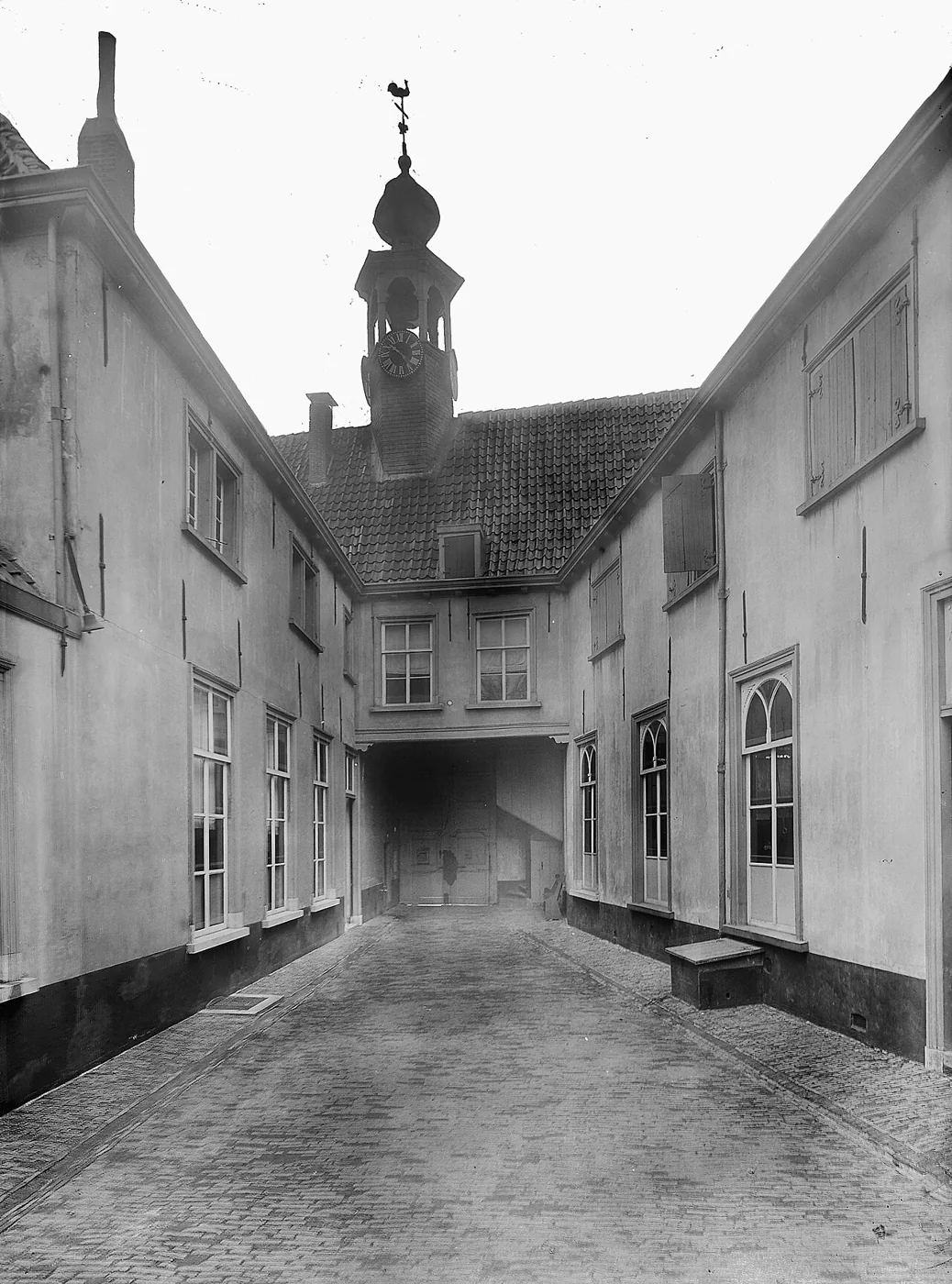 Historic black-and-white photograph of the courtyard with windows and a small bell tower.
