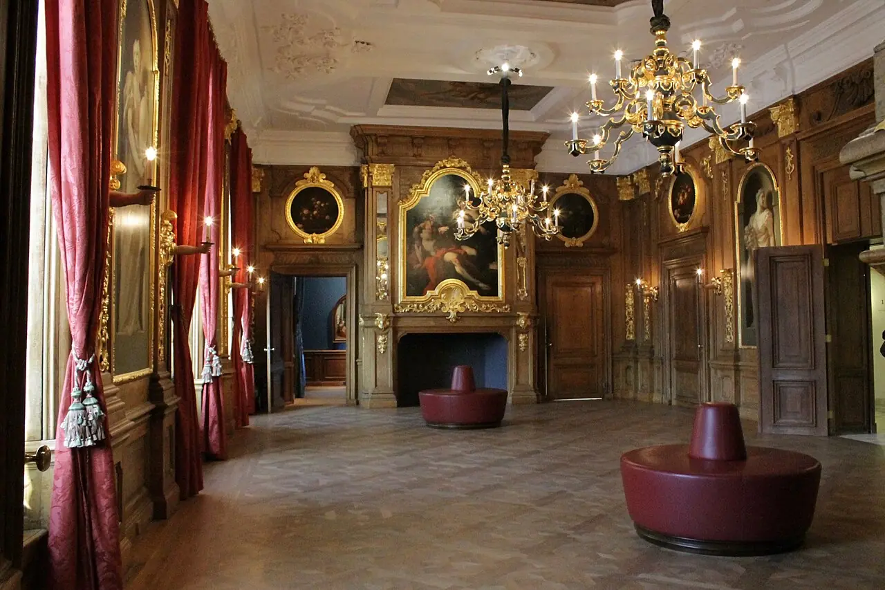 Interieur van een zaal in het Mauritshuis met schilderijen en kroonluchters.